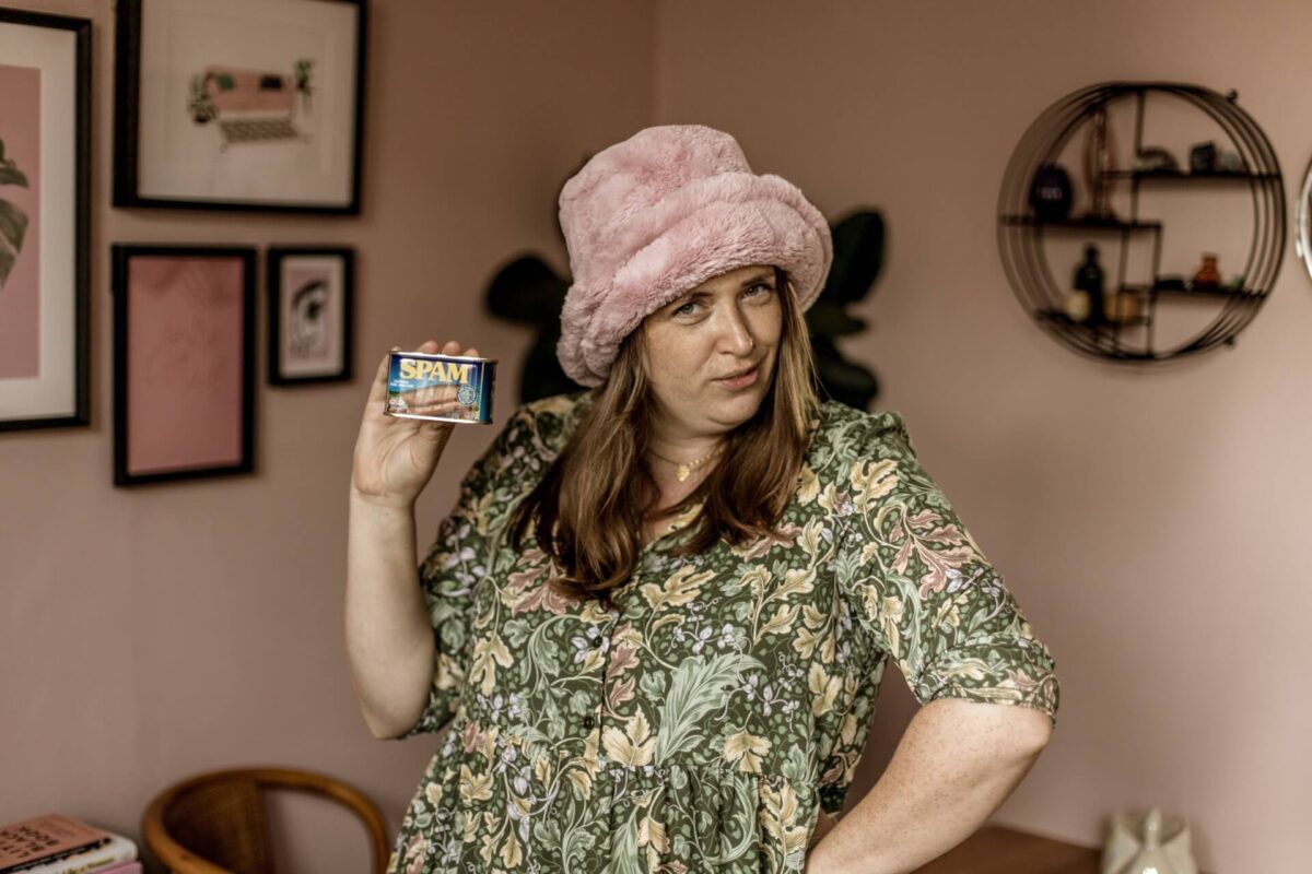 Aime from Studio Cotton posing with a tin of spam and wearing a pink fluffy hat