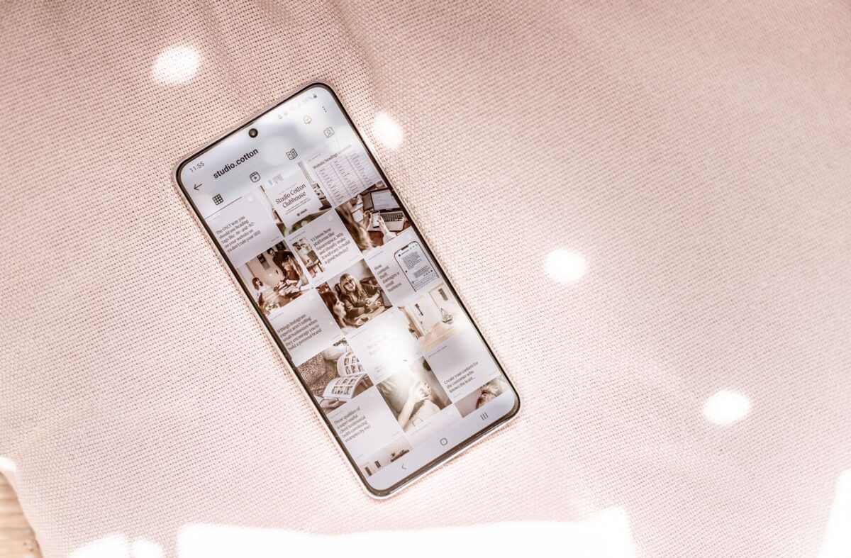 A phone showing the Studio Cotton Instagram grid, resting on a pink fabric background.
