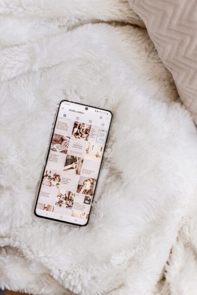 A phone showing the Studio Cotton Instagram grid, resting on a fluffy white fabric background.