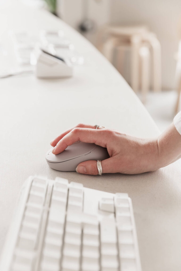 Hands holding a mouse in front of a keyboard.