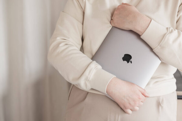 A close up of a closed MacBook Laptop held in Studio Cotton Aime's arms.